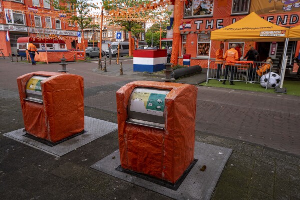 Even two underground garbage containers are covered in orange tarp, as more orange bunting, and Dutch national flags decorate Marktweg street in The Hague, Netherlands, Thursday June 13, 2024, one day ahead of the start of the Euro 2024 Soccer Championship. The Marktweg is one of several streets in the Netherlands that get an all-encompassing orange facelift during European Championships and World Cups when the national team, known as Oranje after the Dutch royal family and the color of their shirts, are playing. (AP Photo/Peter Dejong)