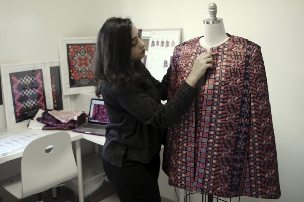 
              In this Tuesday, Jan. 29, 2019 photo, designer Natalie Tahhan works on a modern version of the traditional Palestinian thobe in her studio in east Jerusalem. Tahhan, a designer based in east Jerusalem, produces capes from digital prints that replicate traditional embroidery stitches, “connecting tradition with what is new and stylish.” The thobe has long been a staple of Palestinian life, sewn by village women and worn at weddings and parties. (AP Photo/Mahmoud Illean)
            