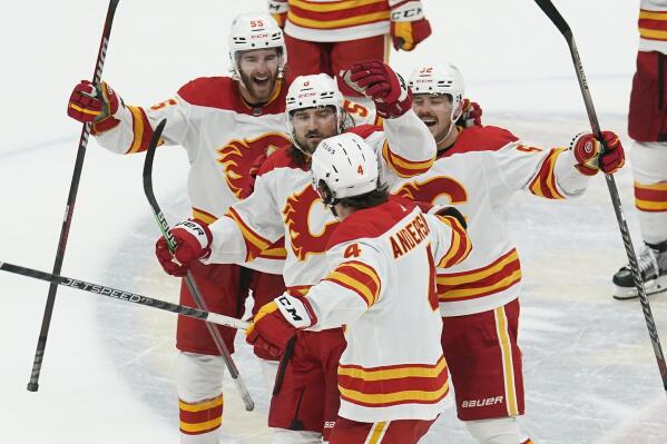Calgary Flames defenseman Rasmus Andersson (4) is congratulated by his teammates after scoring the game winning goal in a shootout at an NHL hockey game against the Florida Panthers, Saturday, Nov. 19, 2022, in Sunrise, Fla. The Flames defeated the Panthers 5-4. (AP Photo/Marta Lavandier)