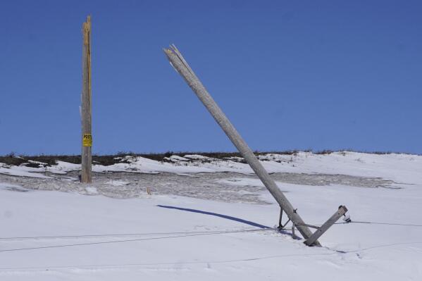 One of several Verendrye Electric Cooperative poles on a line along a Ward County road south of Minot, N.D., snapped in two on Monday, April 25, 2022, after a weekend storm due to heavy ice on the power lines. Weather problems have left at least 19,000 people in western North Dakota facing days without power and thousands of residents along the Red River that separates that state from Minnesota dealing with flash flooding. (Jill Schramm/Minot Daily News via AP)
