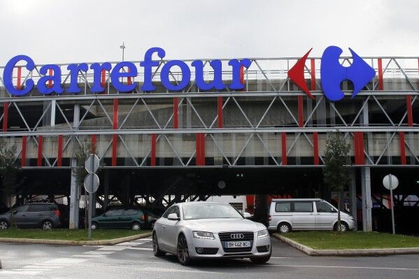 FILE - Car leaves a Carrefour supermarket in Anglet, southwestern France, on Jan.23, 2018. Global supermarket chain Carrefour will stop selling PepsiCo products in its stores in France, Belgium, Spain and Italy over price increases for popular items like Lay's potato chips, Quaker Oats, Lipton tea and its namesake soda. (AP Photo/Bob Edme, File)