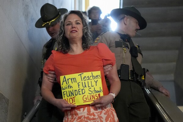 Allison Polidor, a gun control advocate, is escorted out of a legislative hearing room by state troopers, as families waited to testify in favor of gun control measures, in Nashville, Tenn., April 18, 2024. (AP Photo/George Walker IV)