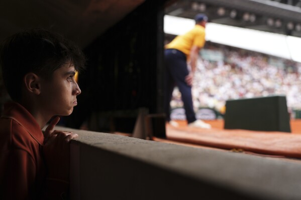 A ball boy follows the fourth round match of the French Tennis Open between China's Zheng Qinwen and Russia's Liudmila Samsonova, at the Roland-Garros stadium, in Paris, Sunday, June 1 2025. (AP Photo/Lindsey Wasson)