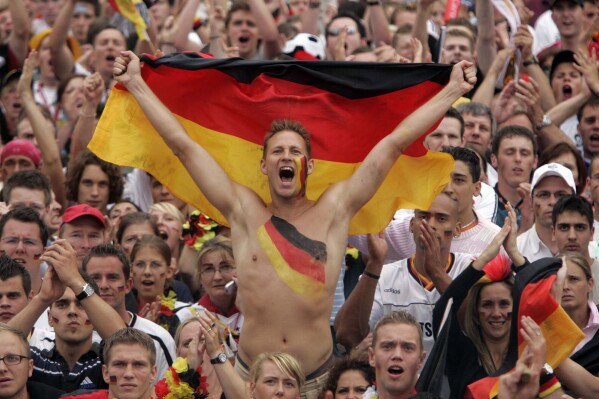 FILE - German soccer fans celebrate while watching the World Cup quarterfinal soccer match between Germany and Argentina at the 'Fan Mile' a public viewing zone in Berlin on Friday, June 30, 2006. Germany gets the 2024 European Championship underway against Scotland in Munich on Friday. However, away from the stadiums and public-viewing areas, few German flags are flying. Germany's dark history, rising far-right cast shadow on national pride before it hosts Euro 2024. (AP Photo/Markus Schreiber, File)