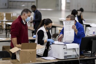 Workers scan ballots as the Fulton County presidential recount gets under way Wednesday morning, Nov. 25, 2020 at the Georgia World Congress Center in Atlanta. Social media users are falsely claiming that missing poll tallies from the 2020 race are proof that 20,713 votes never existed. (AP Photo/Ben Gray)