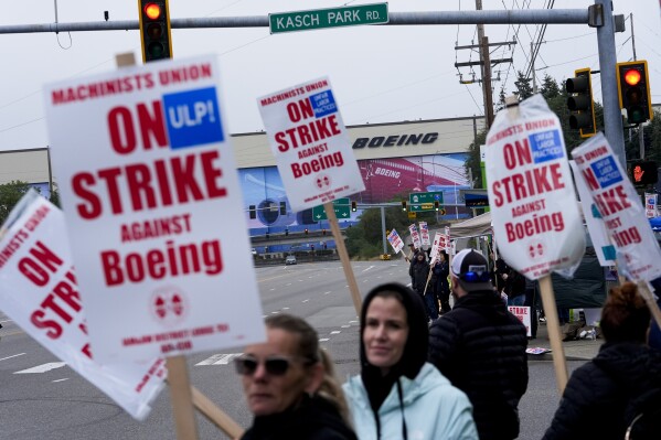 Boeing workers wave picket signs as they strike after union members voted to reject a contract offer near the company's factory in Everett, Washington, Sept. 15, 2024. (AP Photo/Lindsey Wasson)
