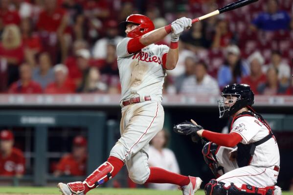 Philadelphia Phillies' Rhys Hoskins, left, watches his two-run home run in front of Cincinnati Reds catcher Michael Papierski during the eighth inning of a baseball game in Cincinnati on Tuesday, Aug. 16, 2022. (AP Photo/Paul Vernon)
