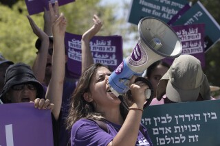 FILE - An Israeli activist leads chants during a protest against plans by Prime Minister Benjamin Netanyahu's government to overhaul the judicial system, in the West Bank settlement of Kdumim, the home of right-wing lawmaker and Minister of Finance Bezalel Smotrich, Friday, July 28, 2023. Israel’s High Court said Tuesday, Sept. 5, it would delay the first of three flashpoint hearings on the legality of the judicial overhaul spearheaded by the far-right government of Netanyahu. (AP Photo/Maya Alleruzzo, File)