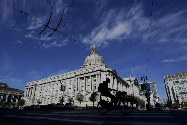 A bicyclist rides past City Hall, which remains open by appointment only, during the coronavirus outbreak in San Francisco, Thursday, Nov. 12, 2020. (AP Photo/Jeff Chiu)