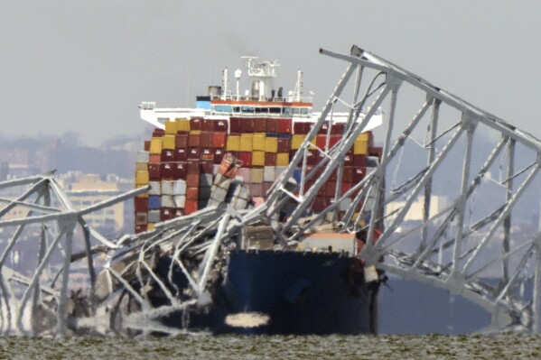 A container ship rests against wreckage of the Francis Scott Key Bridge on Tuesday, March 26, 2024, as seen from Venice on the Bay, Md. (AP Photo/Mark Schiefelbein)