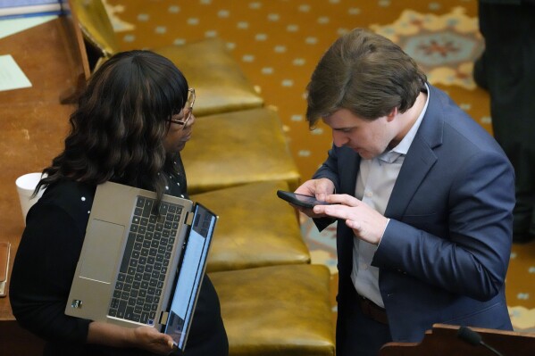 Mississippi House Education Committee vice chairman Rep. Kent McCarty, R-Hattiesburg, right, reviews notes on his smartphone as he answers a question from Rep. Omeria Scott, D-Laurel, following the House passing the Mississippi Student Funding Formula, Friday, April 26, 2024, at the Mississippi State Capitol in Jackson. The Mississippi Student Funding Formula is a new plan that would give districts a boost in funding for students who can be more expensive to educate. (AP Photo/Rogelio V. Solis)