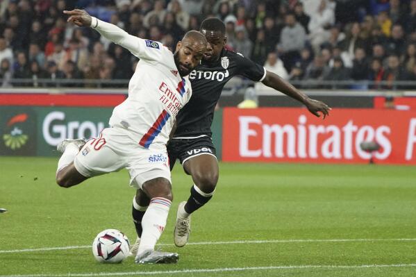 Lyon's Alexandre Lacazette, left, kicks the ball ahead of Monaco's Eliot Matazo during the French League One soccer match between Lyon and Monaco at the Groupama stadium, in Decines, near Lyon, France, Friday, May 19, 2023. (AP Photo/Laurent Cipriani)