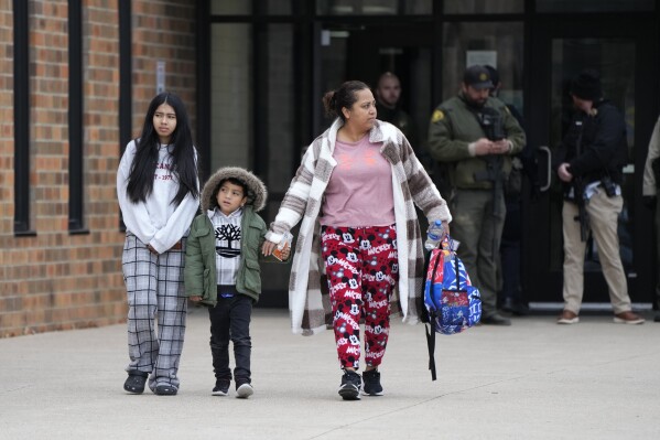 A family leaves the McCreary Community Building after being reunited following a shooting at Perry High School, Thursday, Jan. 4, 2024, in Perry, Iowa. (AP Photo/Charlie Neibergall)