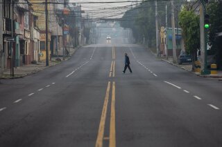 A woman crosses an street that's empty due to a tight lockdown in Guatemala City, early Friday, May 15, 2020. The government decreed a three-day, nationwide lockdown starting Friday to help contain the spread of the new coronavirus. (AP Photo/Moises Castillo)