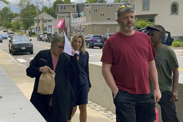 Denise Lodge, left, covers her face with a printout of the indictment against her as she walks from the federal courthouse, Wednesday, June 14, 2023, in Concord, N.H., following her arrest on charges related to an alleged scheme to steal and sell donated body parts. (Steven Porter/The Boston Globe via AP)