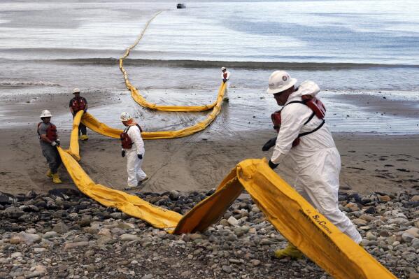 FILE - Workers prepare an oil containment boom at Refugio State Beach, north of Goleta, Calif., on May 21, 2015, two days after an oil pipeline ruptured, polluting beaches and killing hundreds of birds and marine mammals. The owner of an oil pipeline that spewed thousands of barrels of crude oil onto Southern California beaches in 2015 has agreed to pay $230 million to settle a class-action lawsuit by fishermen and property owners, court documents showed Friday, May 13, 2022. (AP Photo/Jae C. Hong, File)