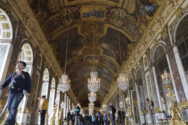 FILE - Visitors walk inside the Hall of Mirrors in the Versailles castle, on Nov. 17, 2015 in Versailles, west of Paris. France is rolling out the red carpet for King Charles III's state visit starting on Wednesday Sept. 20, 2023 at one of its most magnificent and emblematic monuments: the Palace of Versailles, which celebrates its 400th anniversary. (AP Photo/Amr Nabil, File)