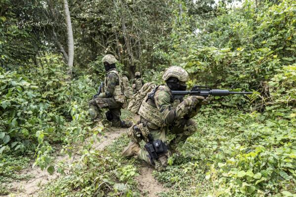Ghanaian special force soldiers taking part in the annual US. Military led counterterrorism training known as Flintlock, patrol under the supervision of British soldiers near base camp Loumbila, Jacqueville, Ivory Coast, Wednesday Feb. 16, 2022. This year's exercises take place as France announces it will be pulling its troops from Mali, where thousands of its soldiers have been fighting Islamic extremists since 2013 when they pushed al-Qaida linked fighters from strongholds in the north. (AP Photo/Sylvain Cherkaoui)