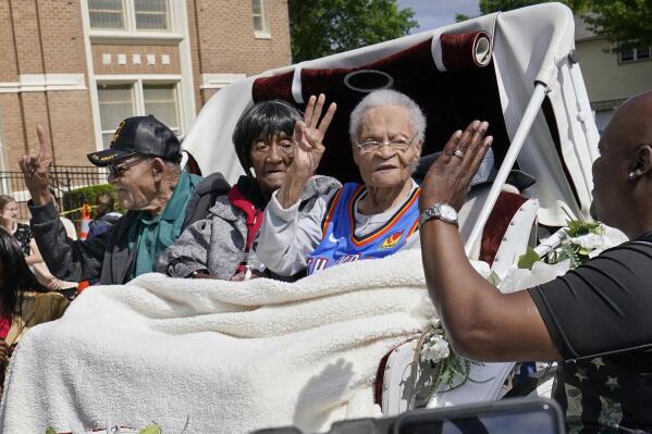 FILE - In this Friday, May 28, 2021 file photo, Tulsa Race Massacre survivors, from left, Hughes Van Ellis Sr., Lessie Benningfield Randle, and Viola Fletcher, wave and high-five supporters from a horse-drawn carriage before a march in Tulsa, Okla. Earlier in the month, the three gave testimony in a panel about the massacre in the U.S. House of Representatives. (AP Photo/Sue Ogrocki)