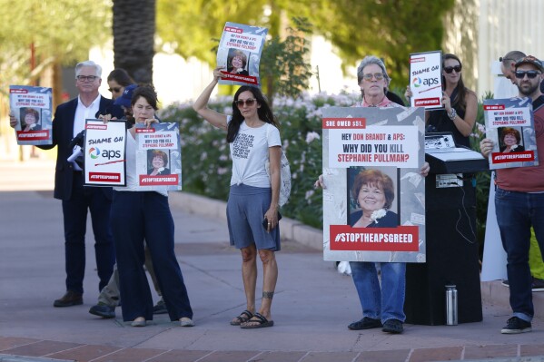 FILE - Stacey Champion, center, holds up a sign with Stephanie Pullman's picture during a protest outside of the Phoenix Art Museum where the Arizona Chamber of Commerce and Industry awards ceremony was celebrating Don Brandt, CEO of Arizona Public Service in Phoenix, Ariz., June 20, 2019. Pullman died in her home after her electricity had been shut off because of a $51 unpaid bill. While Arizona power companies are now banned from cutting off customers during the hottest months, last year nearly 3 million people had their power disconnected for failing to pay bills — a third within the three hottest summer months, according to data collected by the Energy Justice Lab. (Patrick Breen/The Arizona Republic via AP, File)