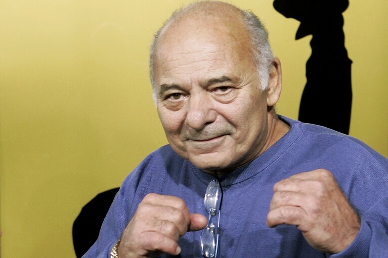 FILE - Burt Young, a cast member of the film "Rocky Balboa," gestures at the premiere of the film in Los Angeles, Dec. 13, 2006. Burt Young, the Oscar-nominated actor who played Paulie, the rough-hewn, mumbling-and-grumbling best friend, corner-man and brother-in-law to Sylvester Stallone in the “Rocky” franchise, has died. Young died Oct. 8, 2023 in Los Angeles. (AP Photo/Kevork Djansezian, File)