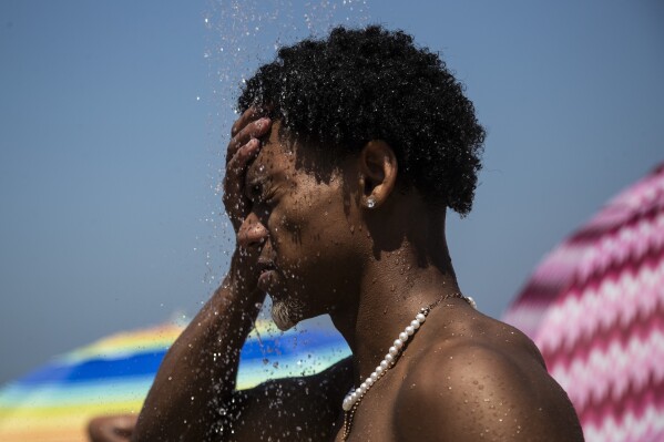 FILE - A man cools off in a shower at Ipanema beach, Rio de Janeiro, Brazil, Sept. 24, 2023. The latest calculations from several science agencies Friday, Jan. 12, 2024, all say that global average temperatures for 2023 shattered existing heat records. (AP Photo/Bruna Prado, File)