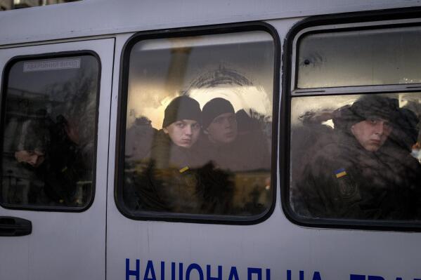 Members of National Guard of Ukraine look out of the window as they ride in a bus through the city of Kyiv, Monday, Feb. 14, 2022. (AP Photo/Emilio Morenatti)