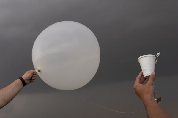 Red team and Project ICECHIP members Wyatt Ficek, left, and Ethan Mok, right, release a latex weather balloon with an attached instrument called a windsond into the inflow region of a storm to collect data during a Project ICECHIP operation Thursday, June 5, 2025, near Morton, Texas. (AP Photo/Carolyn Kaster)