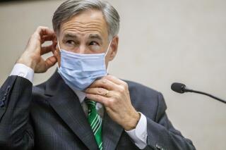 FILE - In this June 16, 2020, file photo, Texas Gov. Greg Abbott adjusts his mask after speaking in Austin, Texas. Abbott on Thursday, July 2, ordered that face coverings must be worn in public across most of the state, a dramatic ramp up of the Republican's efforts to control spiking numbers of confirmed coronavirus cases and hospitalizations. (Ricardo B. Brazziell/Austin American-Statesman via AP, File)