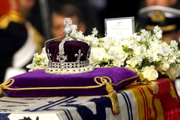 FILE - The Koh-i-noor, or "mountain of light," diamond, set in the Maltese Cross at the front of the crown made for Britain's late Queen Mother Elizabeth, is seen on her coffin, along with her personal standard, a wreath and a note from her daughter, Queen Elizabeth II, as it is drawn to London's Westminster Hall in this April 5, 2002. Hundreds of thousands of people are expected to flock to London’s medieval Westminster Hall from Wednesday, Sept. 14, 2022, to pay their respects to Queen Elizabeth II, whose coffin will lie in state for four days until her funeral on Monday. (AP Photo/Alastair Grant, File)