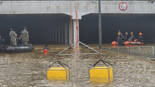 In this photo provided by South Korea National Fire Agency, rescuers search for survivors along a road submerged by floodwaters leading to an underground tunnel in Cheongju, South Korea, Sunday, July 16, 2023. Days of heavy rain triggered flash floods and landslides and destroyed homes, leaving scores of people dead and forcing thousands to evacuate, officials said Sunday.(South Korea National Fire Agency via AP)