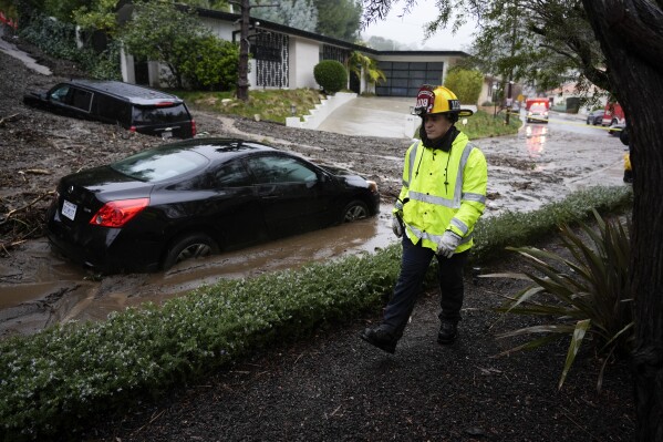 A firefighter walks past vehicles submerged by a mudslide Monday, Feb. 5, 2024, in the Beverly Crest area of Los Angeles. (AP Photo/Marcio Jose Sanchez)