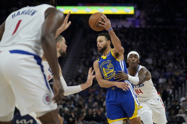 Golden State Warriors guard Stephen Curry (30) passes the ball while defended by Los Angeles Clippers guard Terance Mann, right, and center Ivica Zubac during the first half of an NBA basketball game Thursday, Nov. 30, 2023, in San Francisco. (AP Photo/Godofredo A. V谩squez)