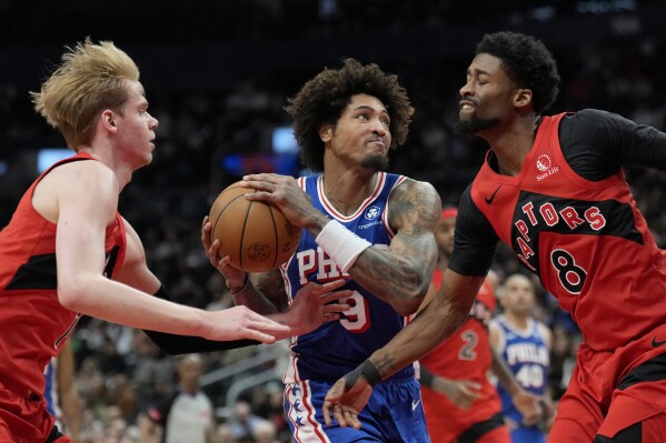 Philadelphia 76ers guard Kelly Oubre Jr. (9) drives to the basket between between Toronto Raptors' Kobi Simmons (8) and Gradey Dick (1) during the second half of an NBA basketball game Sunday, March 31, 2024, in Toronto. (Frank Gunn/The Canadian Press via AP)