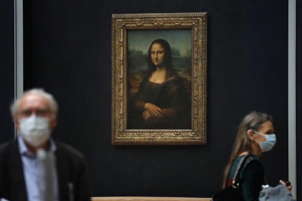 FILE - Journalists walk past Leonardo da Vinci's Mona Lisa during a visit of the Louvre museum Tuesday, June 23, 2020. Using X-rays to peer into the chemical structure of a tiny speck of the celebrated work of art, scientists have gained new insight into the techniques that Leonardo da Vinci used to paint his groundbreaking portrait of the woman with the exquisitely enigmatic smile. (AP Photo/Christophe Ena, File)