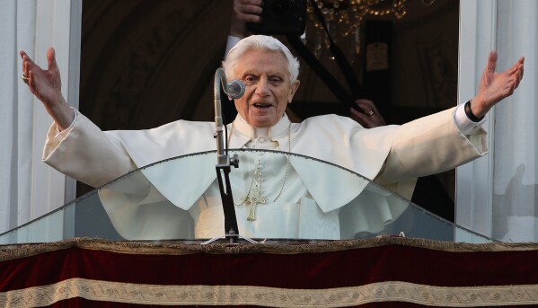 FILE- In this Thursday, Feb. 28, 2013 file photo, Pope Benedict XVI greets the crowd from the window of the Pope's summer residence of Castel Gandolfo, the scenic town where he will spend his first post-Vatican days and make his last public blessing as pope. A book of interviews with the Polish Rev. Mieczyslaw Mokrzycki, “Secretary of Two Popes,” released May 2017, has offered some insight into the daily life at the Vatican with John Paul and his German-born successor, Benedict XVI. (AP Photo/Andrew Medichini, File)