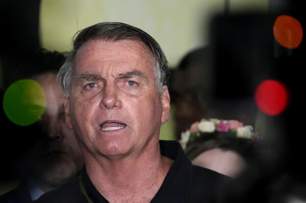 Former President Jair Bolsonaro speaks to the press after being formally charged by the federal police with attempted coup, at the airport in Brasilia, Brazil, Monday, Nov. 25, 2024. (AP Photo/Eraldo Peres)