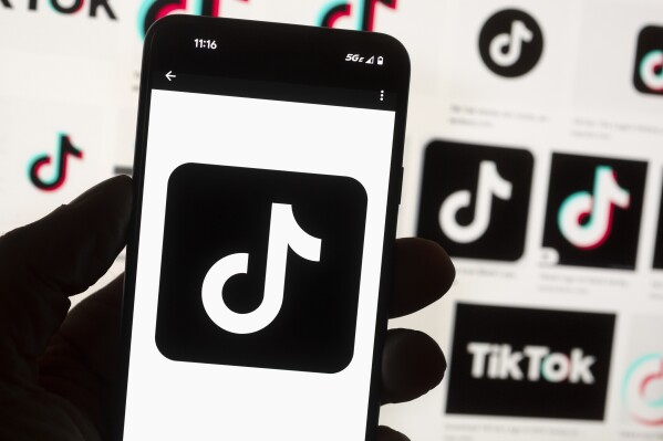 FILE - The TikTok logo is displayed n a mobile phone in front of a computer screen displaying the TikTok home screen, Oct. 14, 2022, in Boston. In a lawsuit filed Tuesday, April 9, 2024, two tribal nations accused social media companies — including Facebook and Instagram’s parent company Meta Platforms; Snapchat's Snap Inc.; TikTok parent company ByteDance; and Alphabet, which owns YouTube and Google — of contributing to the disproportionately high rates of suicide among Native American youth. (AP Photo/Michael Dwyer, File)