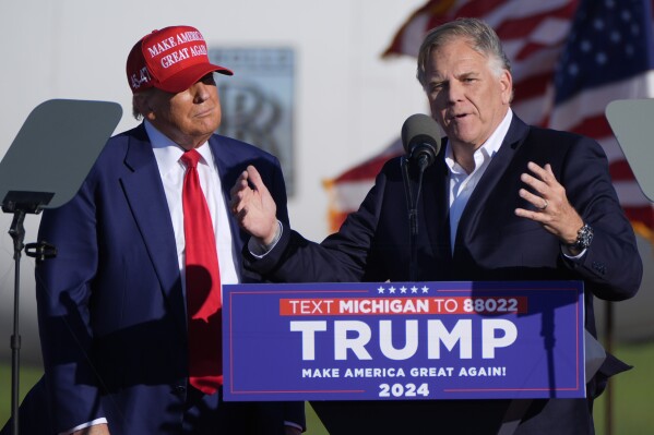 Republican presidential candidate former President Donald Trump listens as Michigan Senate candidate former Rep. Mike Rogers speaks at a campaign rally in Freeland, Mich., Wednesday, May 1, 2024. (AP Photo/Paul Sancya)