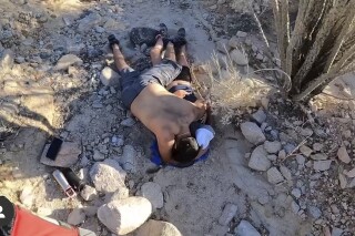 This still image from video provided by the Riverside County Sheriff's Office shows two hikers lying on the ground as Riverside County Sheriff's Aviation Unit's Rescue 9 was dispatched to the Ladder Canyon Trail in Mecca, Calif., to assist the hikers, who were requesting medical aid, June 9, 2024. The couple, hiking in the desert south of Joshua Tree National Park in Southern California, was rescued after running out of water. The Riverside County Sheriff's Office says a man called 911 and reported that his girlfriend was dehydrated and weak. (Riverside County Sheriff's Office via AP)