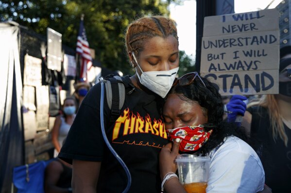 Ryann Davis, left, of Bowie, Md., comforts Diamond Fayne, of Norfolk, Va., after Fayne burst into tears while attending a protest Sunday, June 7, 2020, near the White House in Washington, over the ...