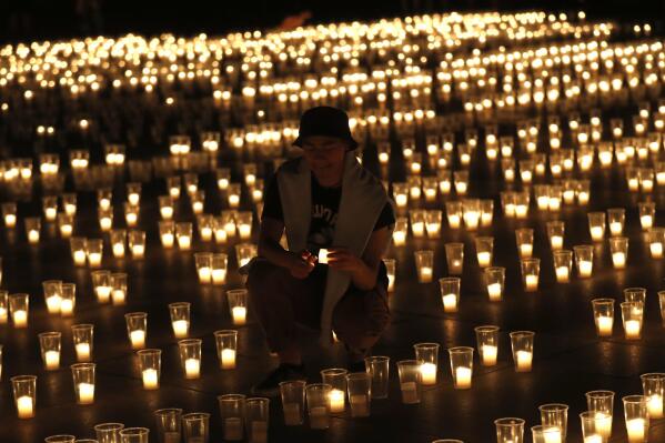 A man lights up candles to commemorate victims of the COVD-19 pandemic at the Prague Castle in Prague, Czech Republic, Monday, May 10, 2021. The Czech Republic is massively relaxing its coronavirus restrictions as the hard-hit nation pays respect to nearly 30,000 dead. (AP Photo/Petr David Josek)