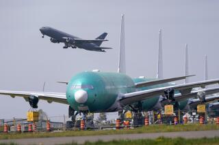 In this April 23, 2021 photo, a U.S. Air Force KC-46A Pegasus jet takes off in view of a line of Boeing 777X jets parked nose to tail on an unused runway at Paine Field, near Boeing's massive production facility in Everett, Wash. Orders to U.S. factories for big-ticket manufactured goods rose for the 12th time in the last 13 months in May, pulled up by a surge in demand for civilian aircraft.(AP Photo/Elaine Thompson)