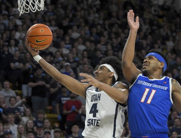 El guardia del estado de Utah, Ian Martínez (4), conduce hacia la canasta mientras el guardia del estado de Boise, Chibuzo Agbo (11), defiende durante la primera mitad de un partido de baloncesto universitario de la NCAA el sábado 10 de febrero de 2024 en Logan, Utah.  (Eli Lucero/The Herald Journal vía AP)