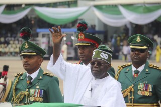 FILE - Nigeria's new President Bola Ahmed Tinubu, inspects honor guards after taking an oath of office at a ceremony in Abuja, Nigeria, on May 29, 2023. Nigeria adopted a new national anthem on Wednesday, May 29, 2024, after lawmakers passed a law that replaced the current one with a version dropped nearly 50 years ago, sparking widespread criticism about how the law was hastily passed without much public input.(AP Photo/Olamikan Gbemiga, File)