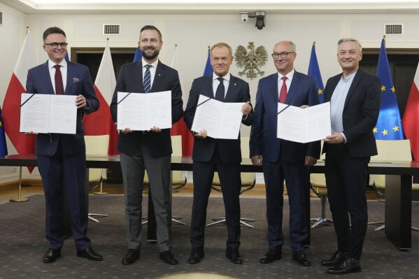 Szymon Holownia, left, head of the Poland 2050 party, Wladyslaw Kosiniak-Kamysz, head of the Polish People's Party, Donald Tusk, center, head of the Civic Coalition, Wlodzimierz Czarzasty, a co-chairman of the New Left party, and Robert Biedron, the other co-chairman of the New Left, sign a coalition agreement, in Warsaw, Poland, on Friday Nov. 10, 2023. The leaders of Polish opposition parties have signed a coalition agreement that lays out a roadmap for governing the nation over the next four years. (AP Photo/Czarek Sokolowski)