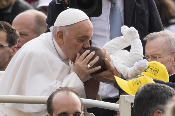Pope Francis kisses a new born as he arrives for his weekly general audience in St. Peter's Square at The Vatican, Wednesday, April 10, 2024. (AP Photo/Andrew Medichini)