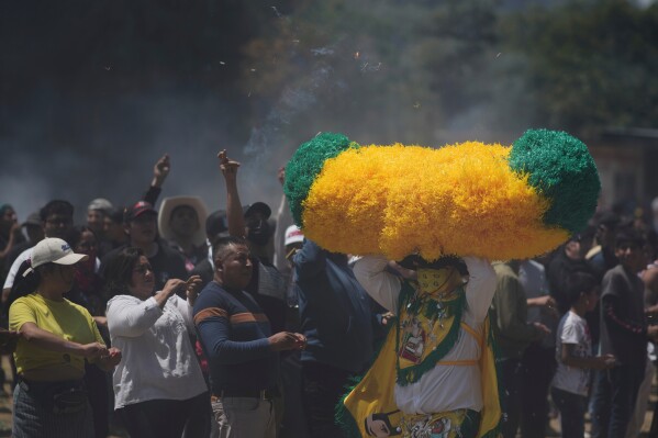 A reveler, known as a sayon, runs with a tissue paper hat as onlookers throw lit matches at him during Easter celebrations in Tetela del Volcan, Mexico, Sunday, April 20, 2025. (AP Photo/Eduardo Verdugo)