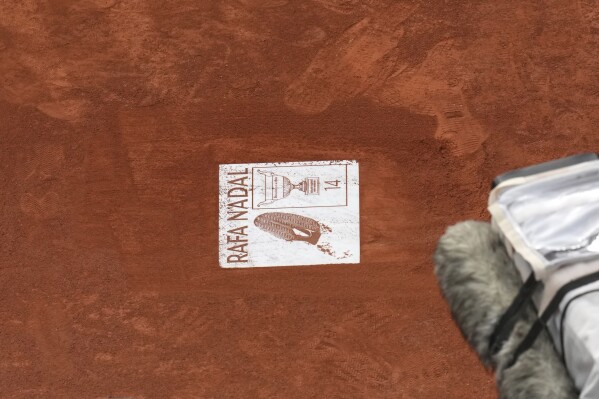 Un cartel de Rafa Nadal se coloca durante una ceremonia de despedida en la cancha central Philippe-Chatrier, en el estadio Roland-Garros, en París, el domingo 25 de mayo de 2025. (Foto AP/Christophe Ena)