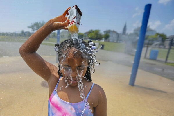 Ja-Veah Cheney, 9, pours water over her head, taking shelter from the sweltering heat at the splash pad station at Riverside Park in New Bedford, Mass., on July 12, 2023. (Peter Pereira/The Standard-Times via AP)